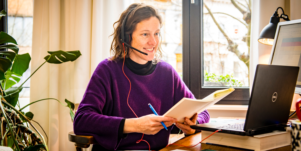 Een vrouw met een headset kijkt op haar laptop. Een vrouw met een headset kijkt op haar laptop.